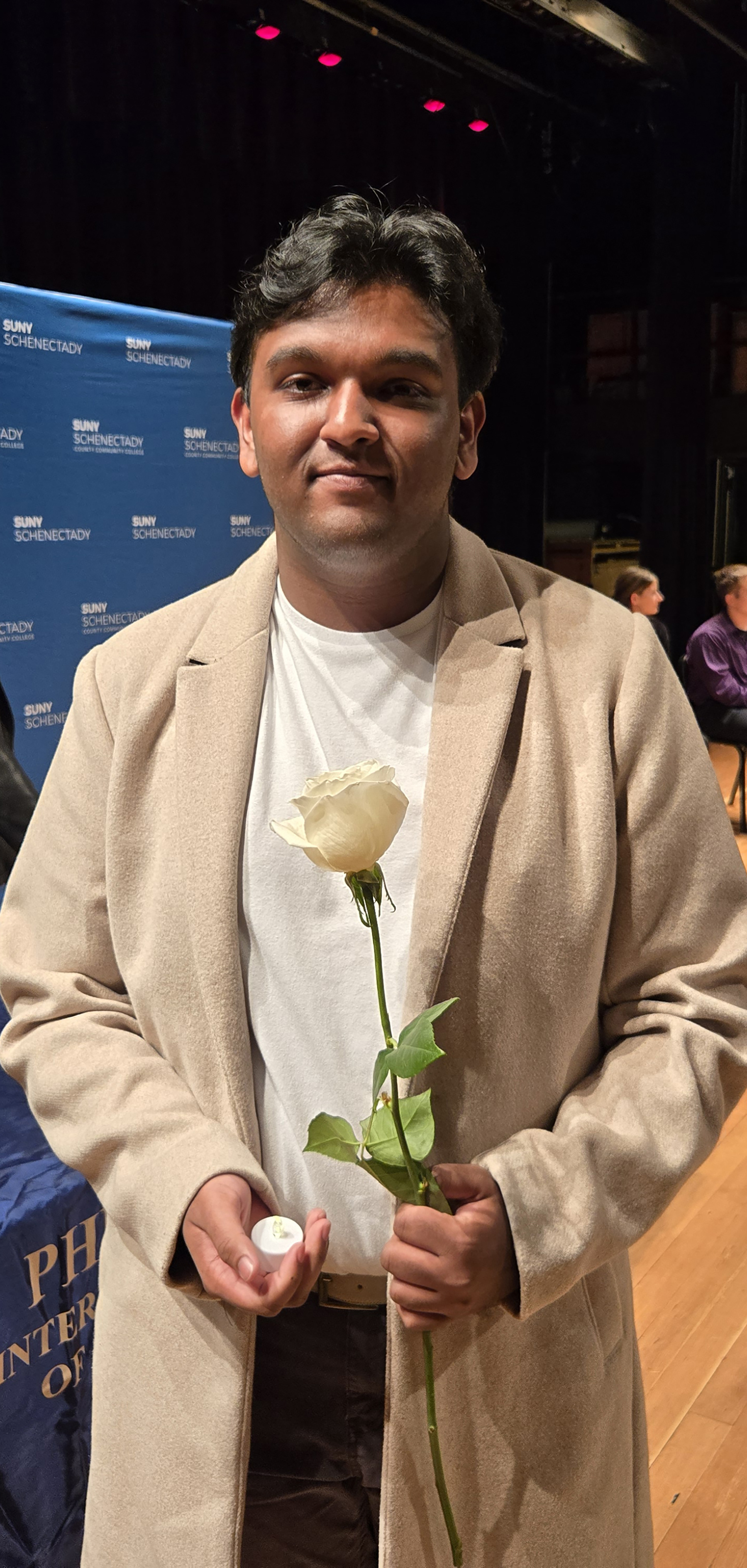 Student holding white rose on stage