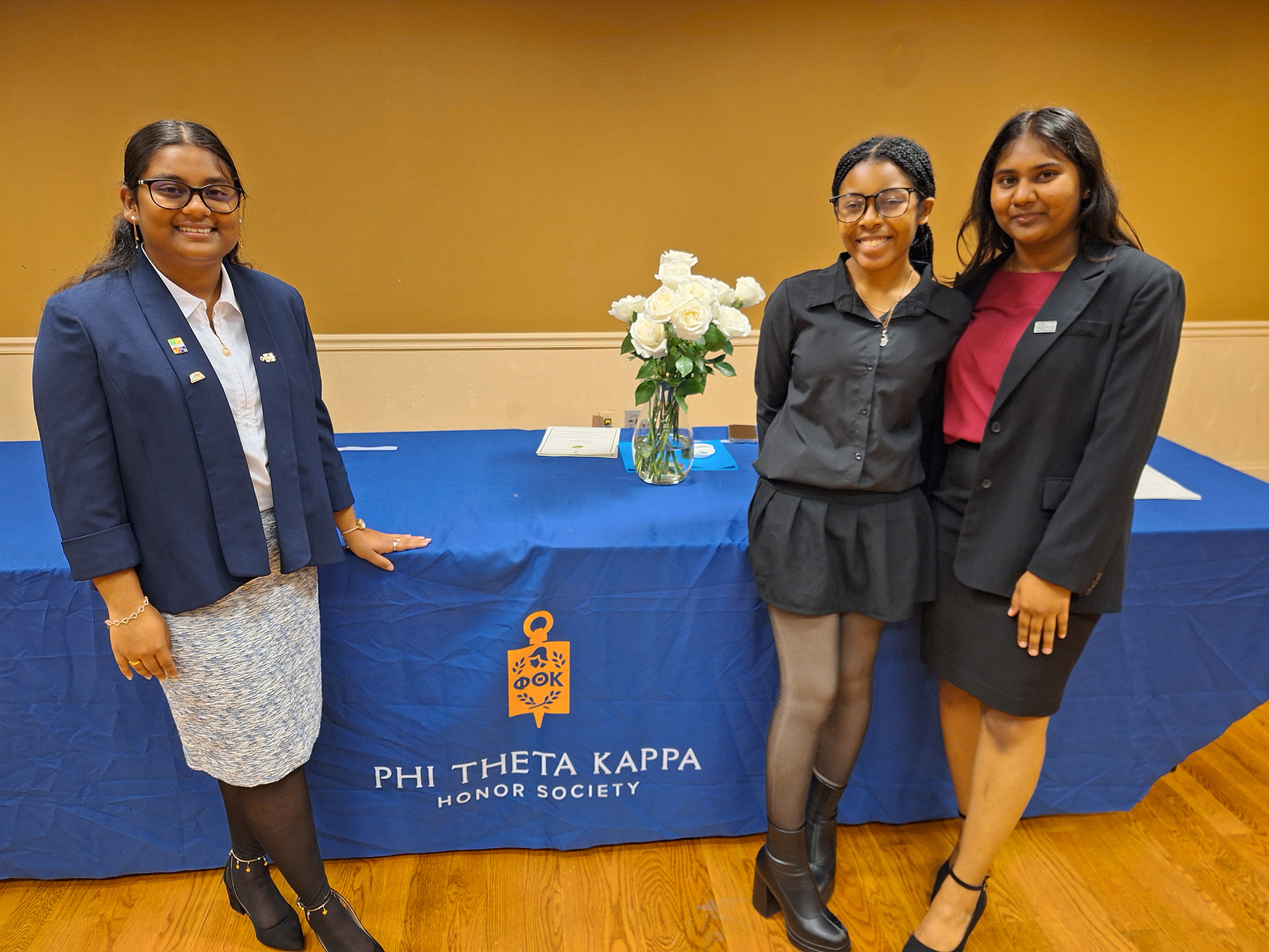 Three PTK Officers standing in front of table with PTK banner on it