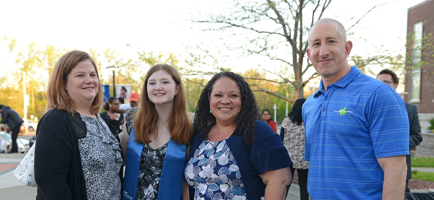 Pam McCall standing outside after ceremony with graduate Abigal Cohen and family