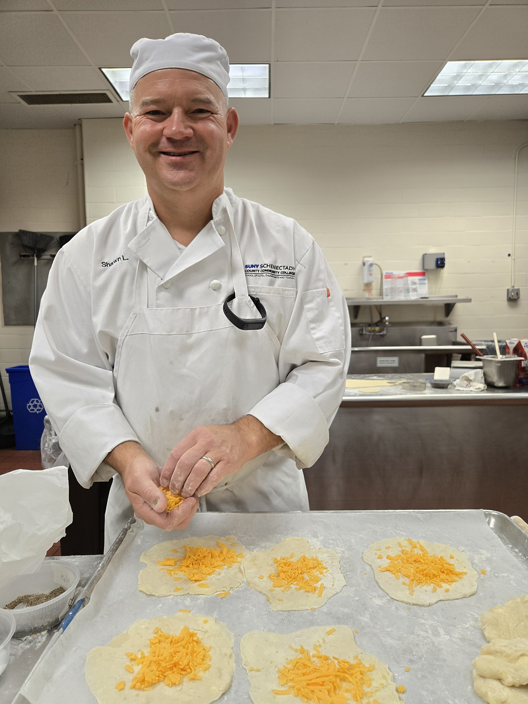 Student smiling, preparing cheese and dough for baking