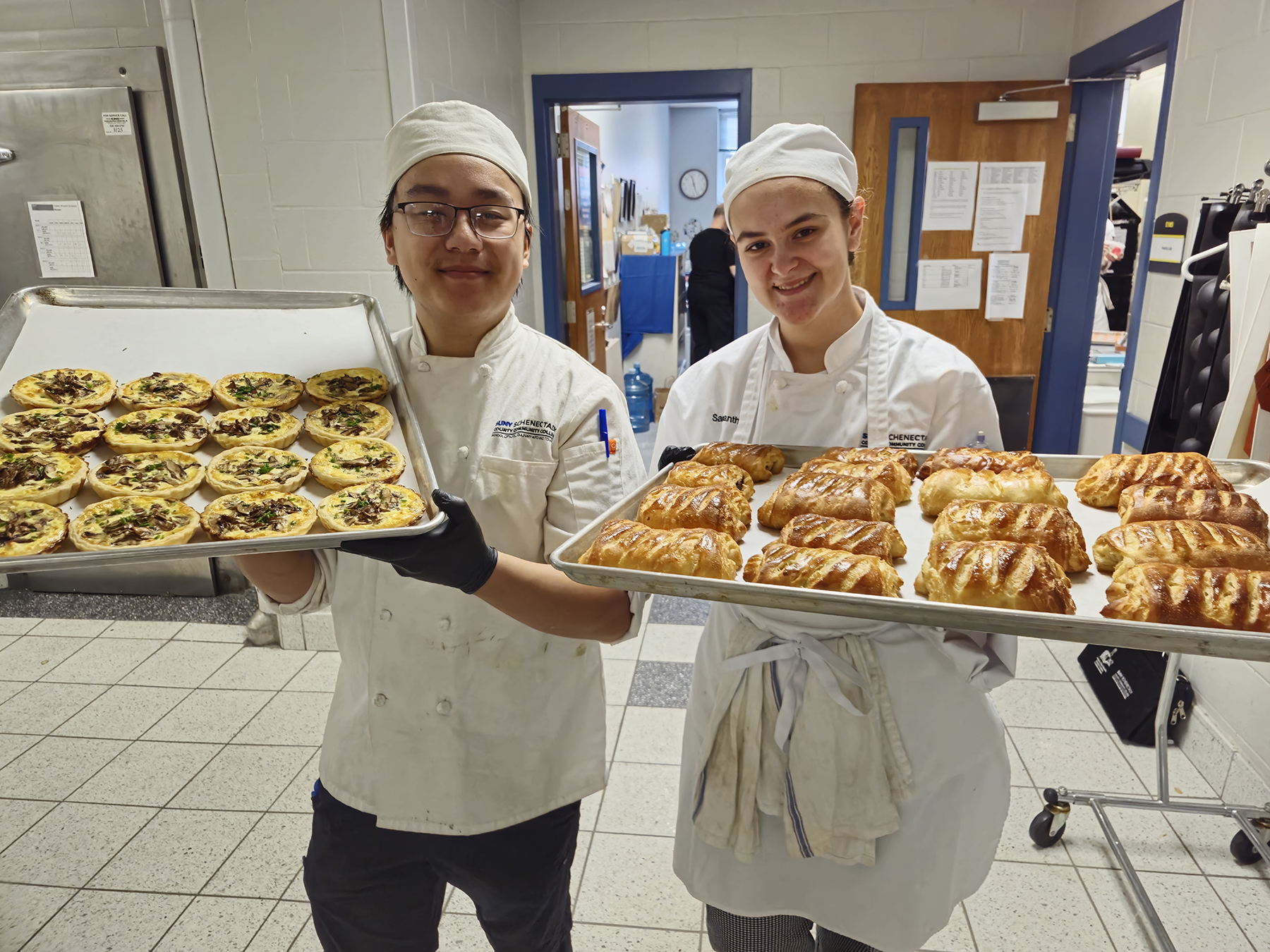 Two student holding trays of baked goods