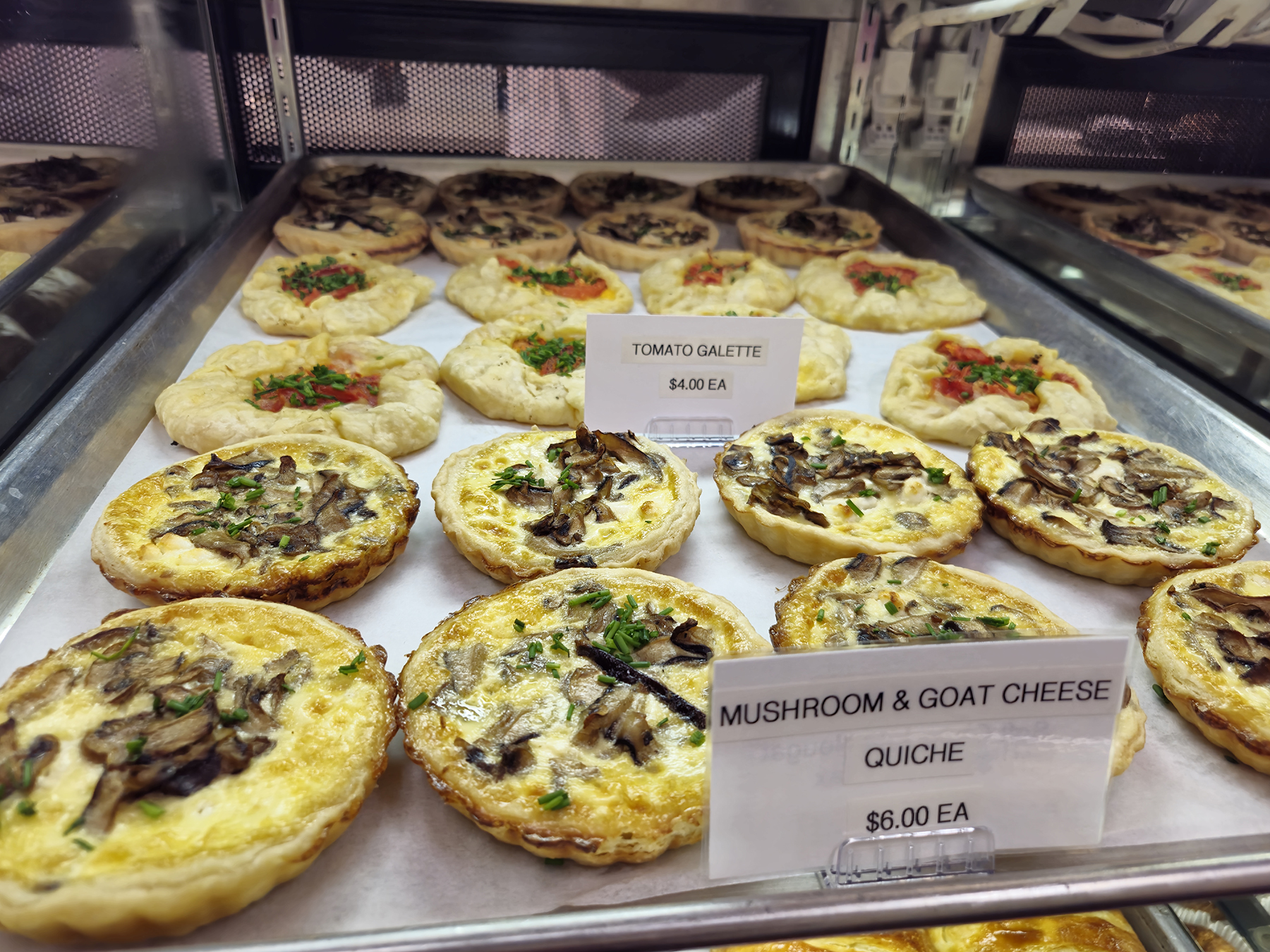 Galettes and quiche on tray inside bakery 