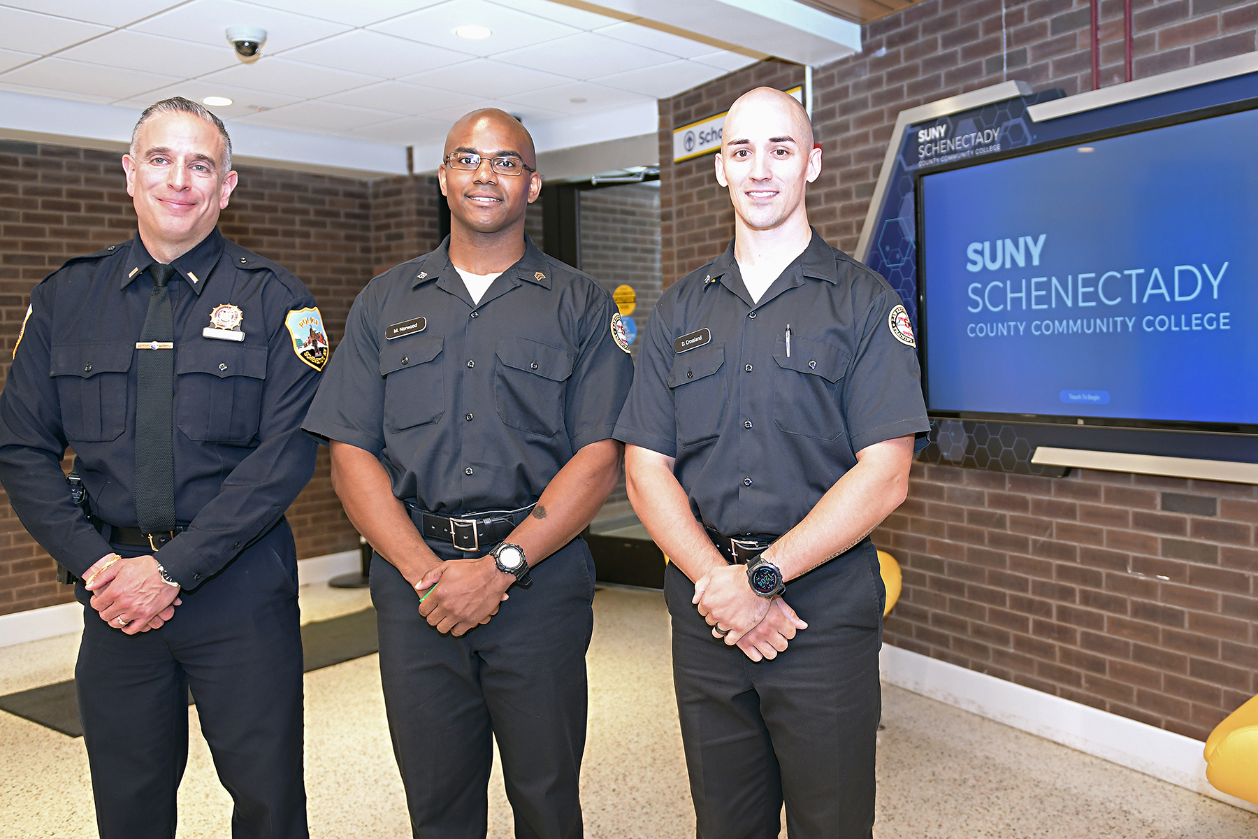 Police lieutenant and two of the recruits standing outside auditorium