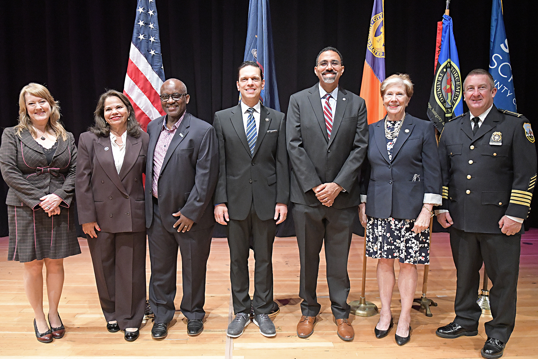 College officials, Department of Labor, SUNY, Schenectady Police Department standing on stage in auditorium