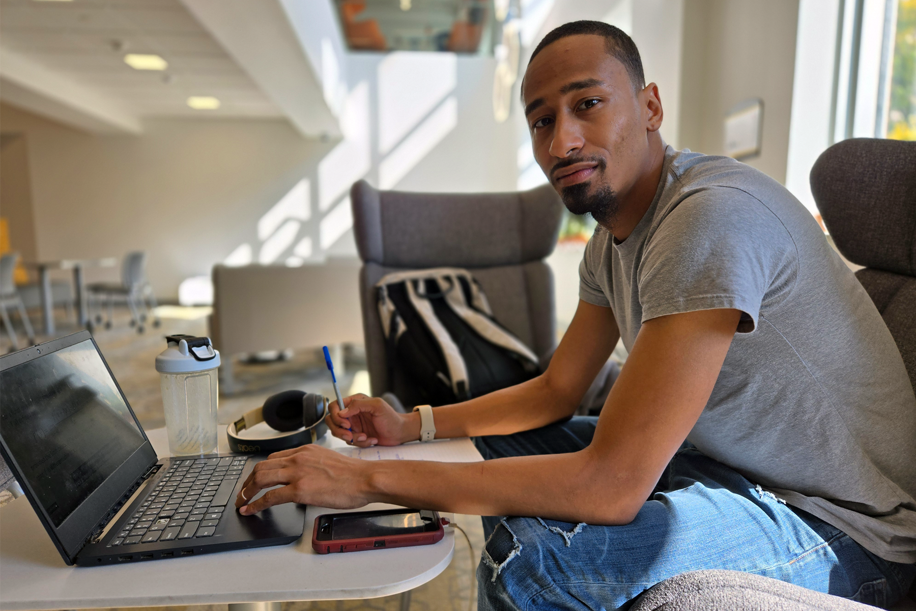 Rayshawn Floyd sitting in library, in front of laptop