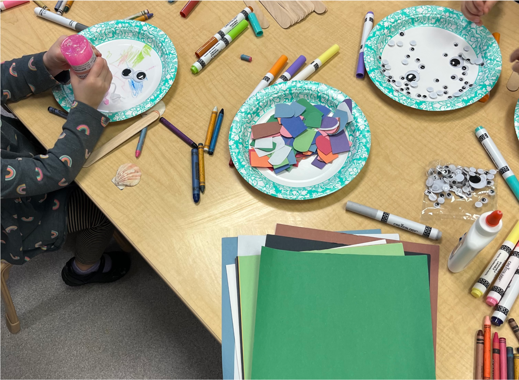 Child seated at table doing artwork