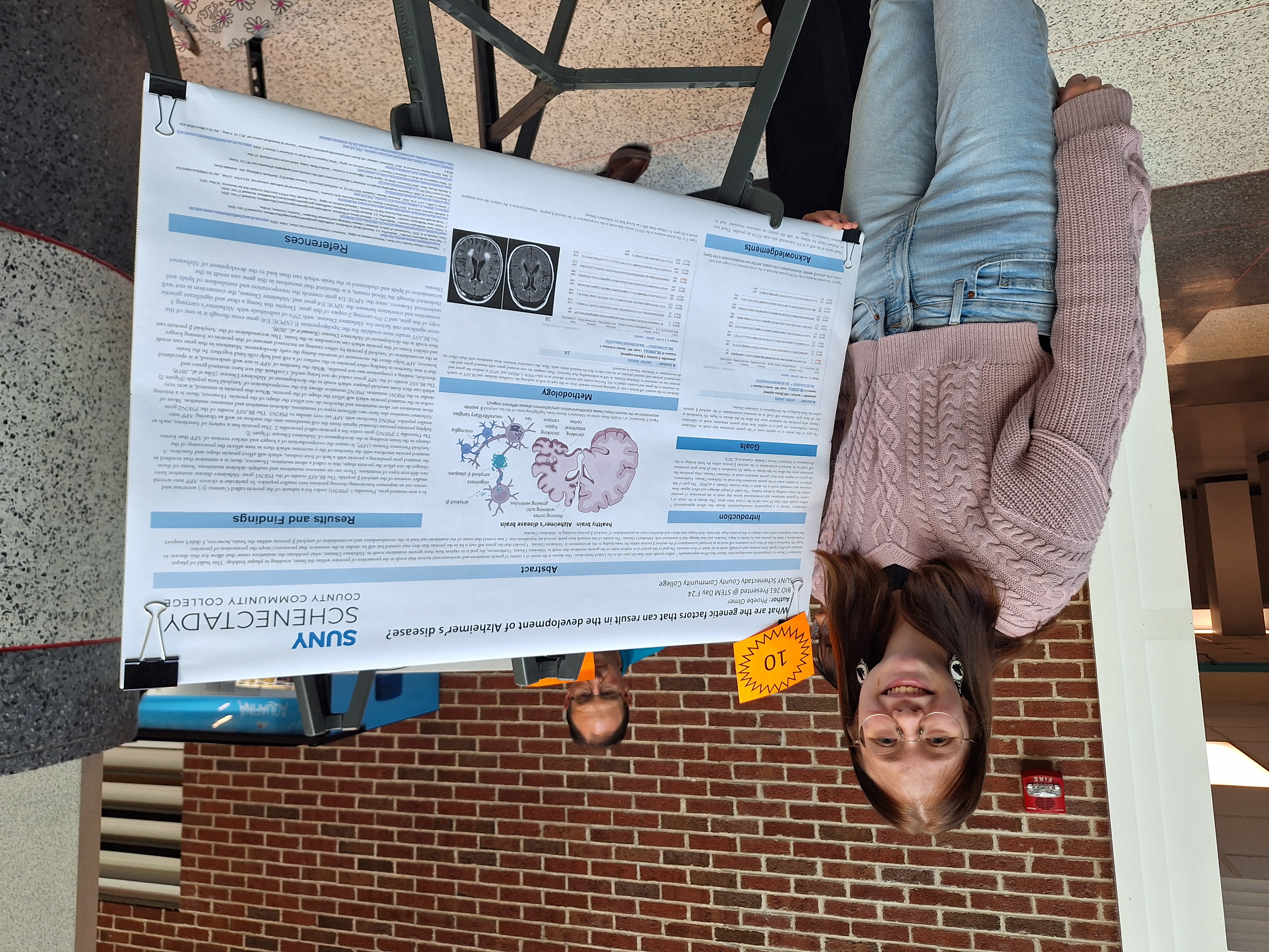 Student standing in front of research poster on easel