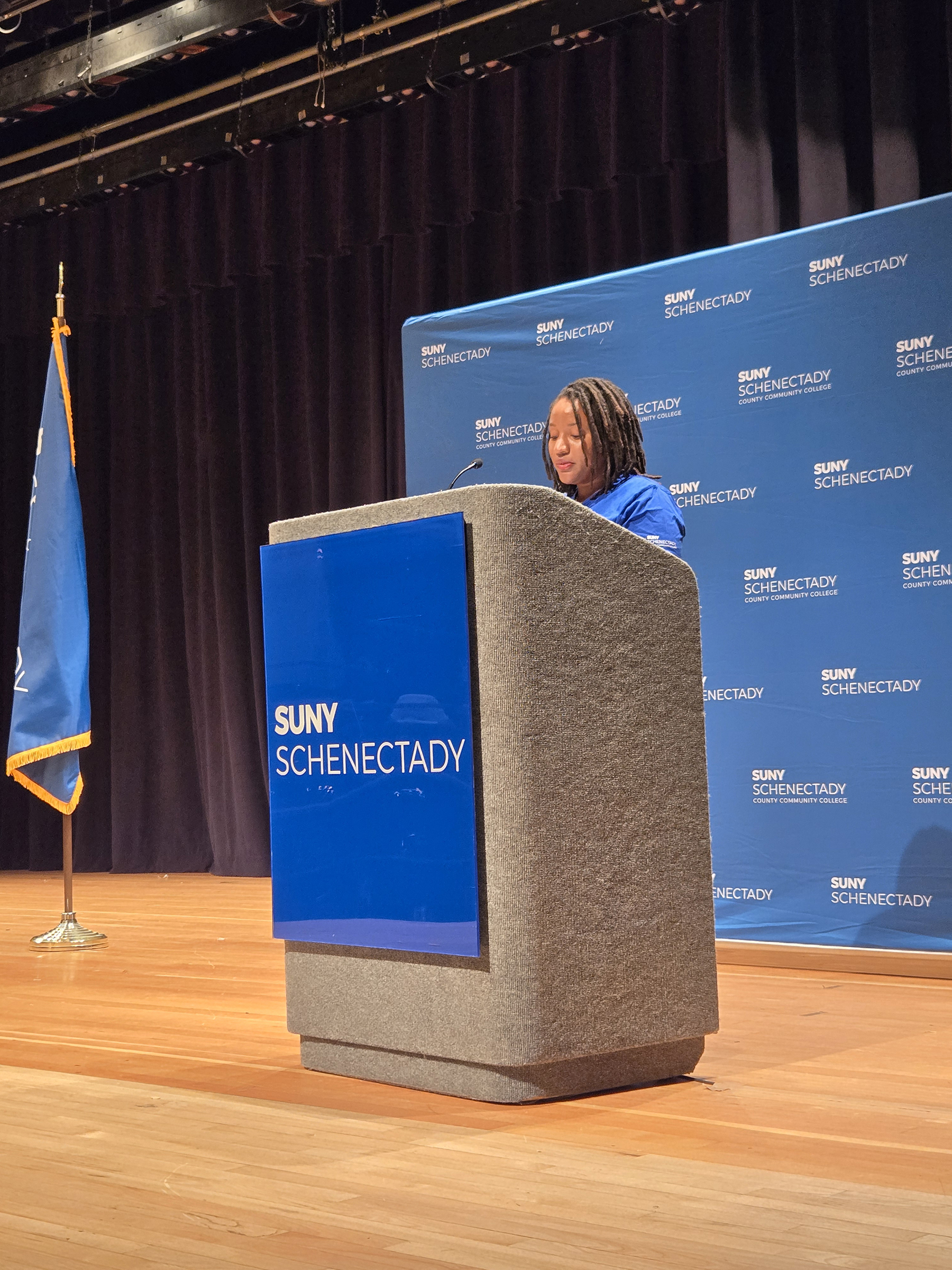 Monique Stamps standing at podium on stage, speaking