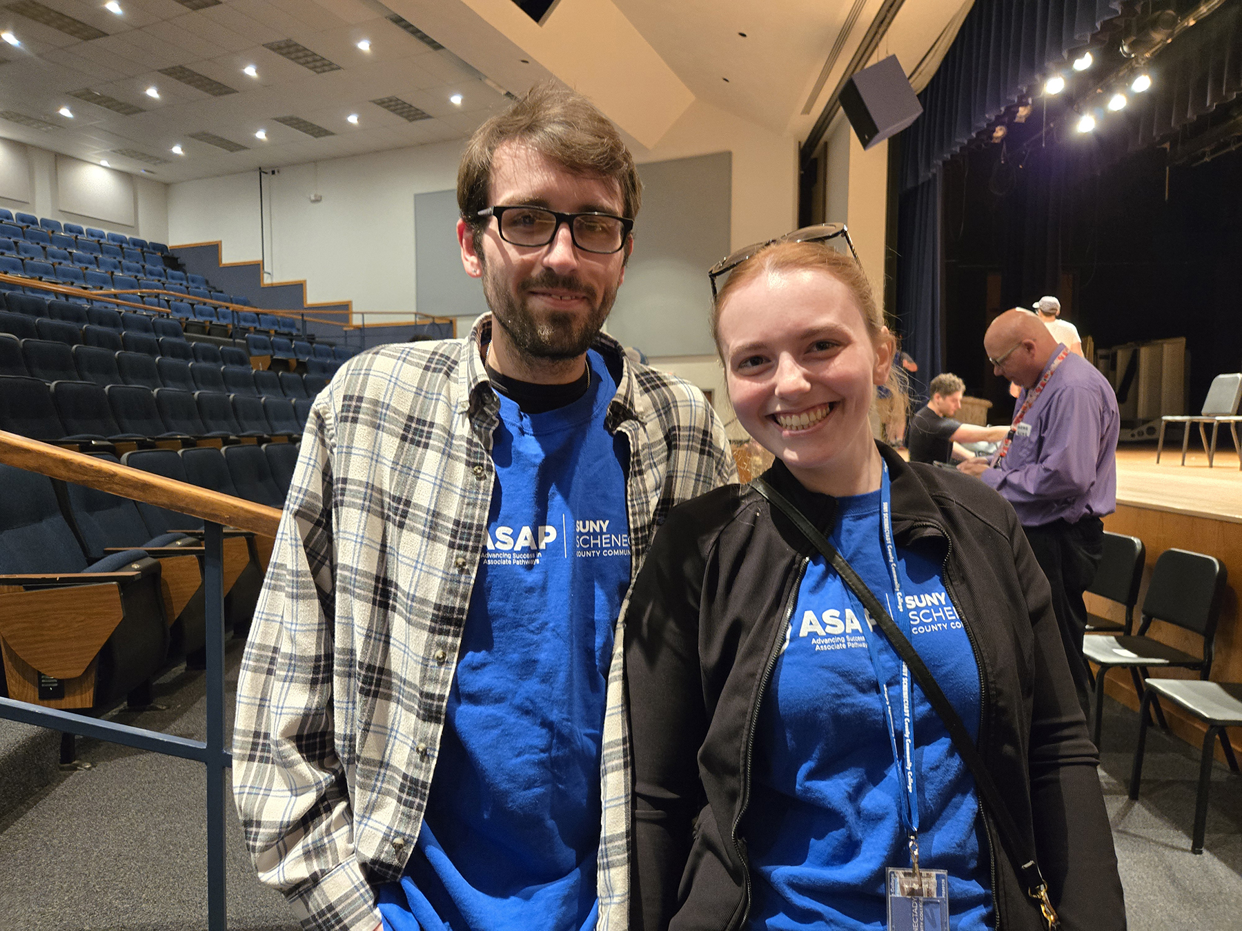Two students, wearing blue ASAP tshirt, standing inside auditorium