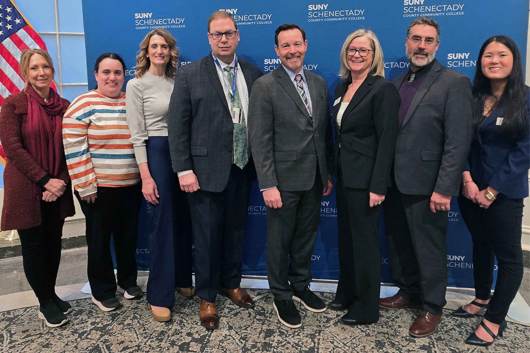 College officials standing in a group in front of SUNY Schenectady backdrop