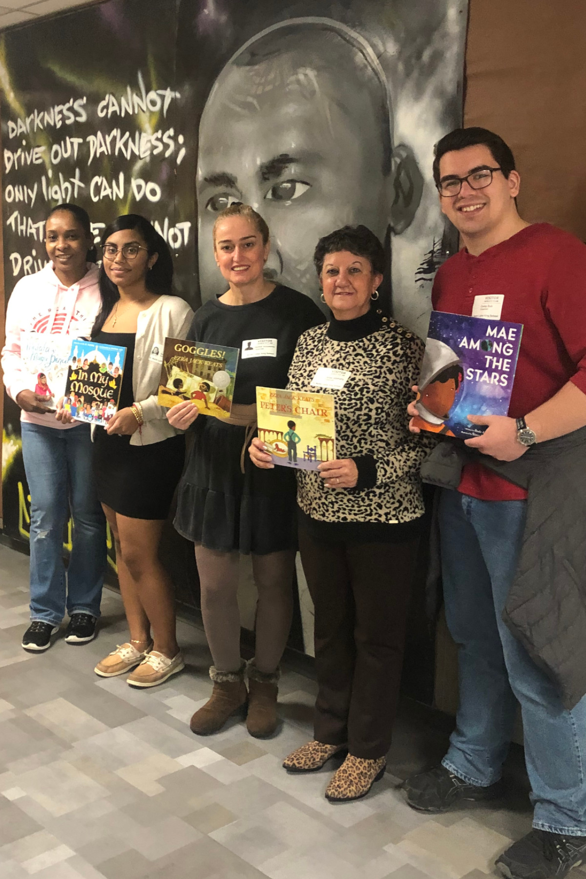 SVO members and advisor holding books in hallway at Martin Luther King Jr. Elementary School. 