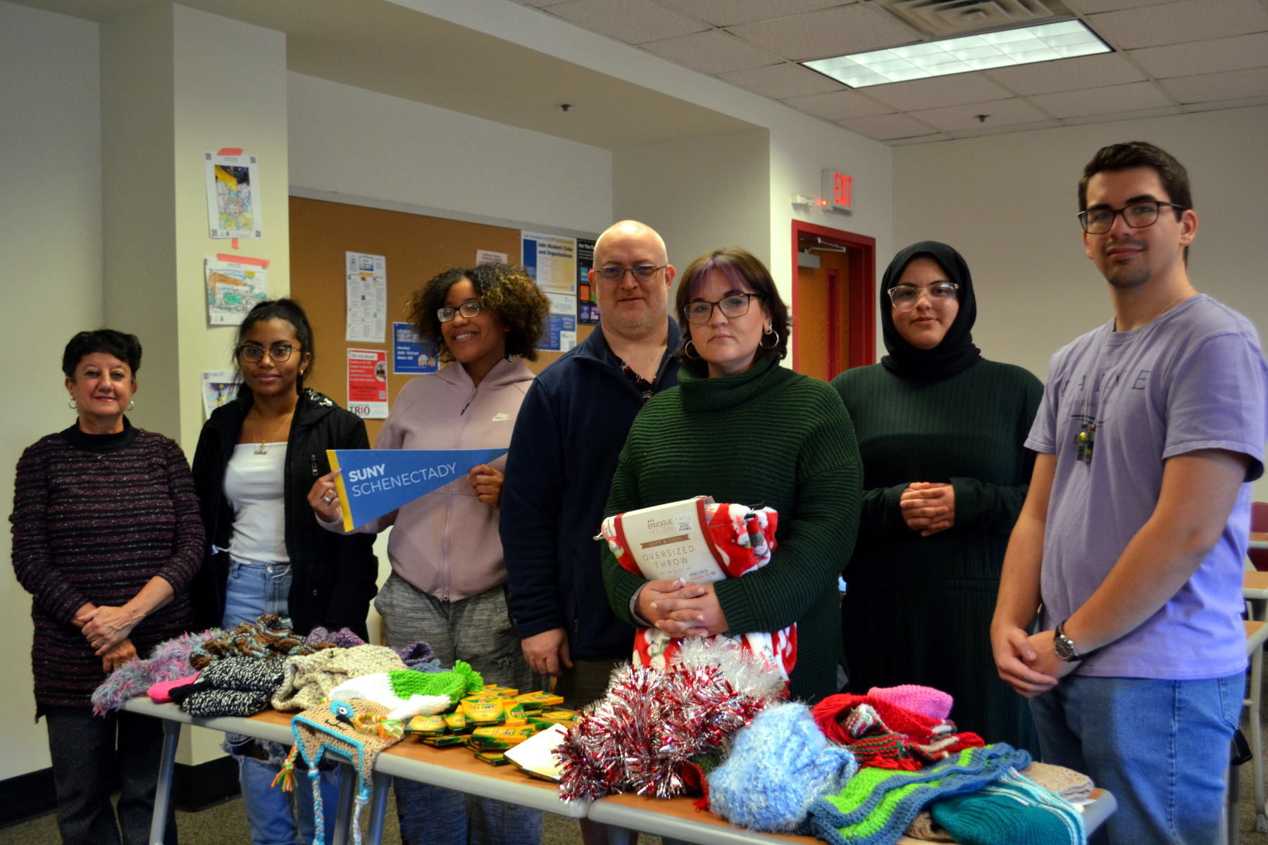 Student Volunteer Organzation members standing behind table that has hats, scarves, and art supplies on it