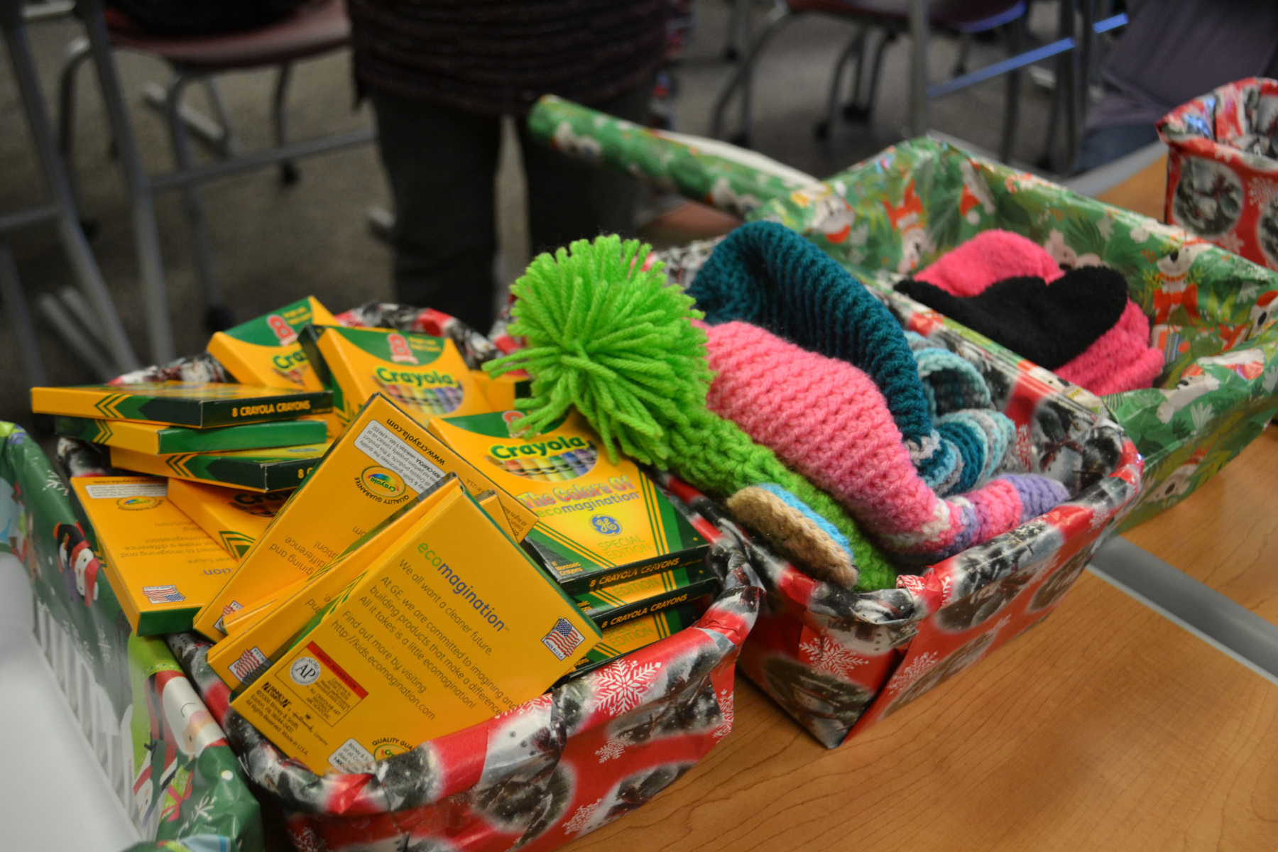 Gift wrapped boxes of hats, scarves and crayons on table