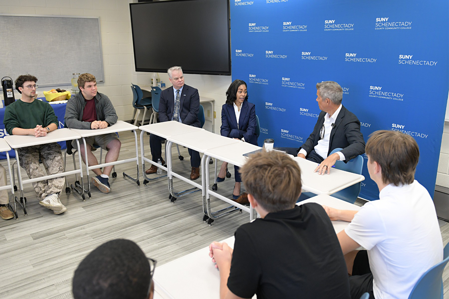 College President Nicole Reaves and Secretary Sean Duffy seated at table having a discussion with students