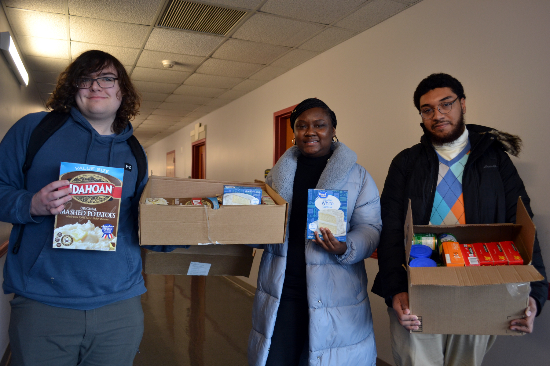 Students holding boxes of Thanksgiving food to be given away