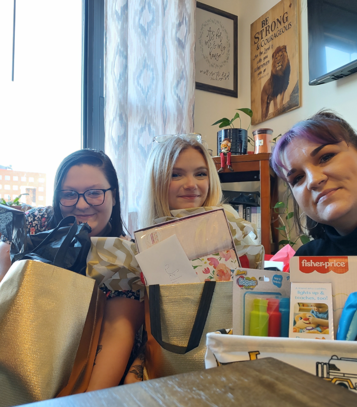 Three students smiling, holding gift bags they put together