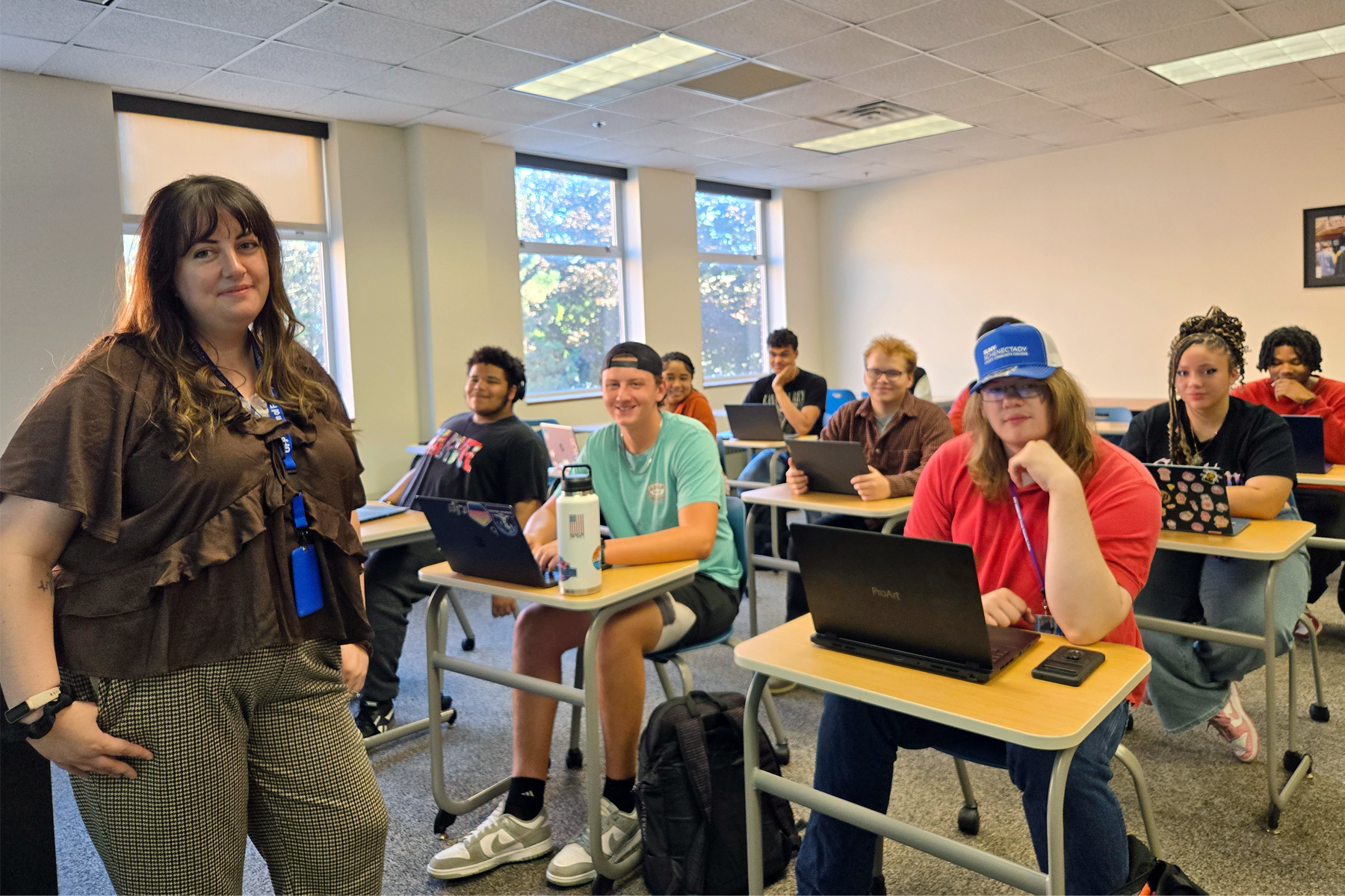 Instructor Shannon Wolf standing at front of classroom, students seated at desks, smilng