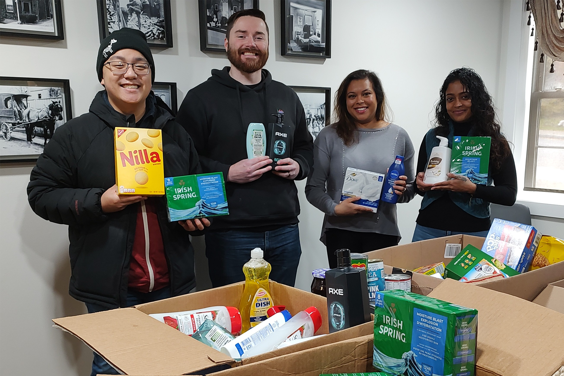 Students holding food items and personal care items that are being donated, standing, smiling