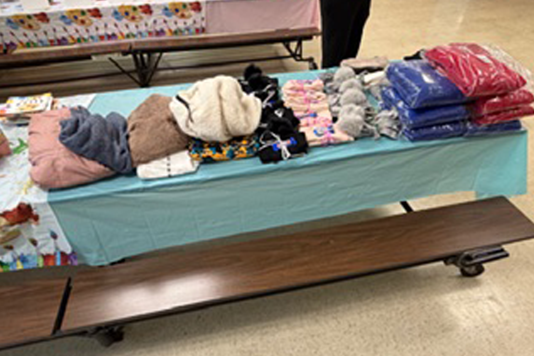 Winter hats, scarves, and blankets on a table.