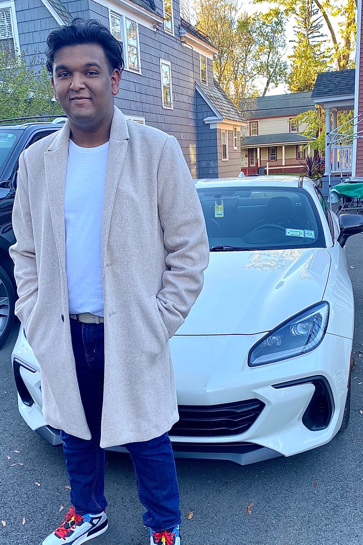 Tejram Khagraj smiling, standing outside in front of white car