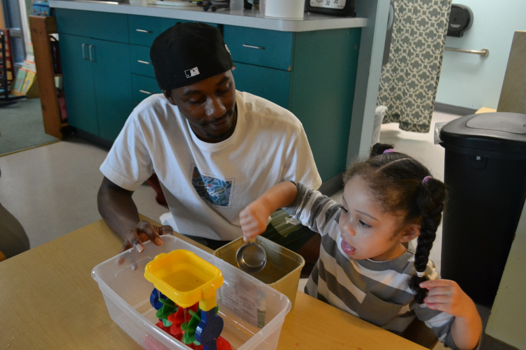 Tyrell Outlaw and student seated at table doing STEM lesson with water and sand