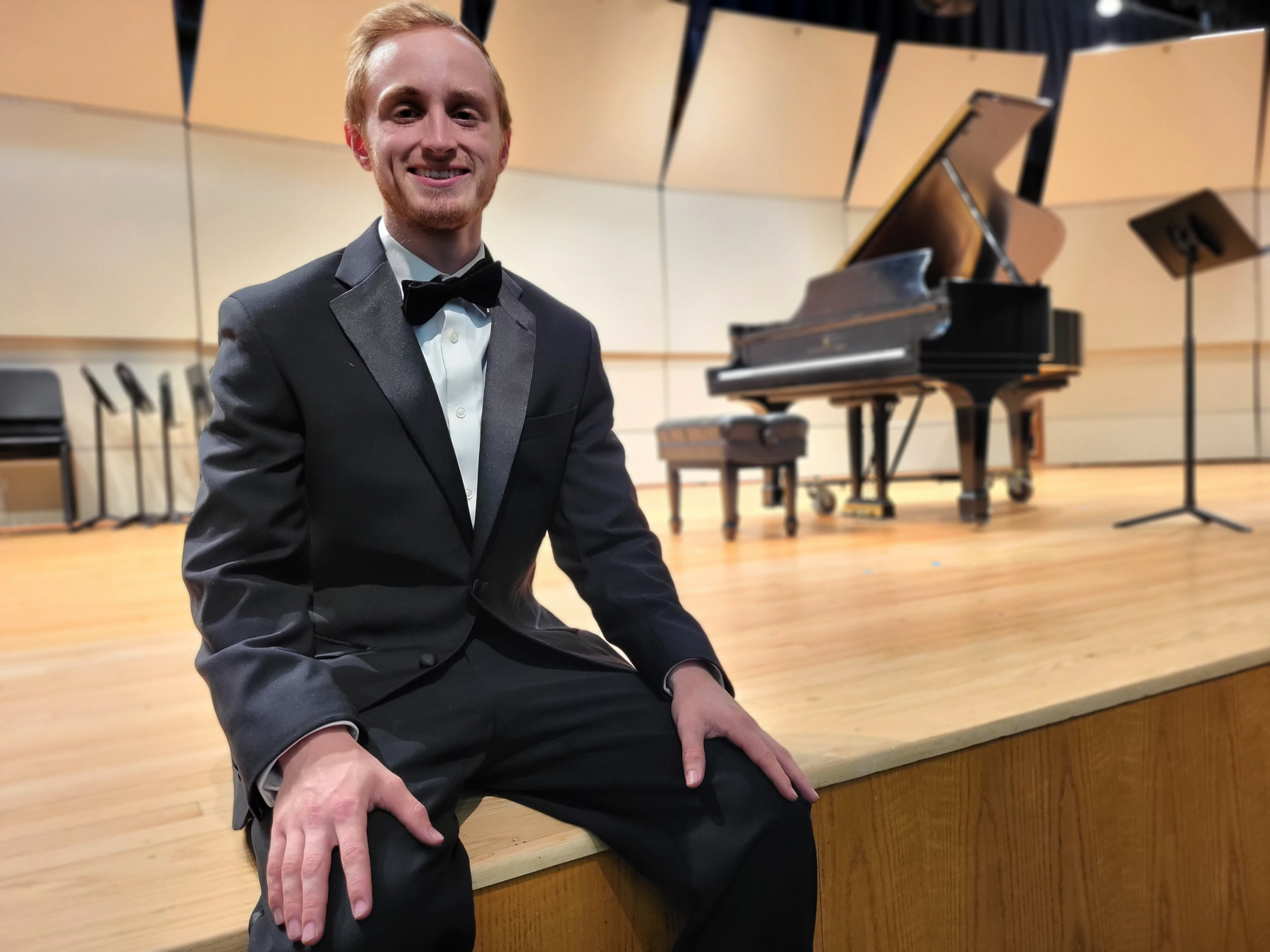 Will Jelstrom wearing tuxedo, sitting on stage in Taylor Auditorium