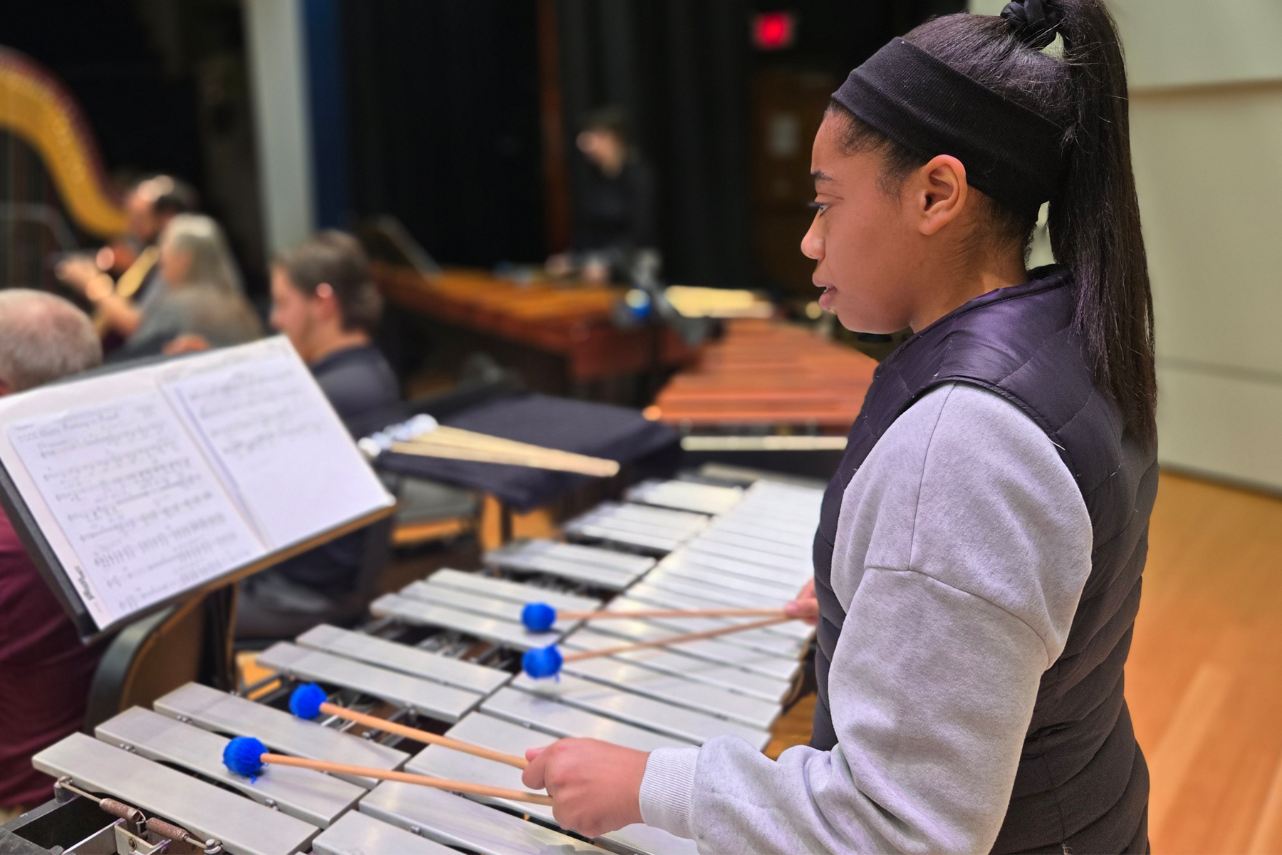 Student playing percussion on stage during Wind Ensemble rehearsal