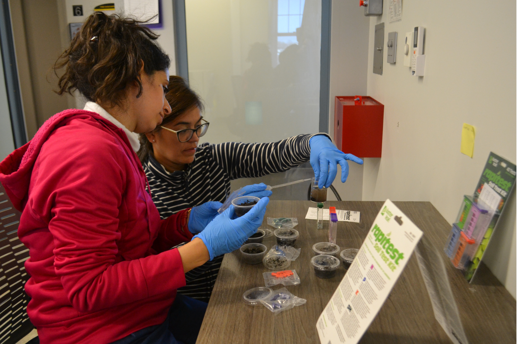 Yasameen Al Salihi and Dr. Lorena Harris sitting at science table analyzing soil