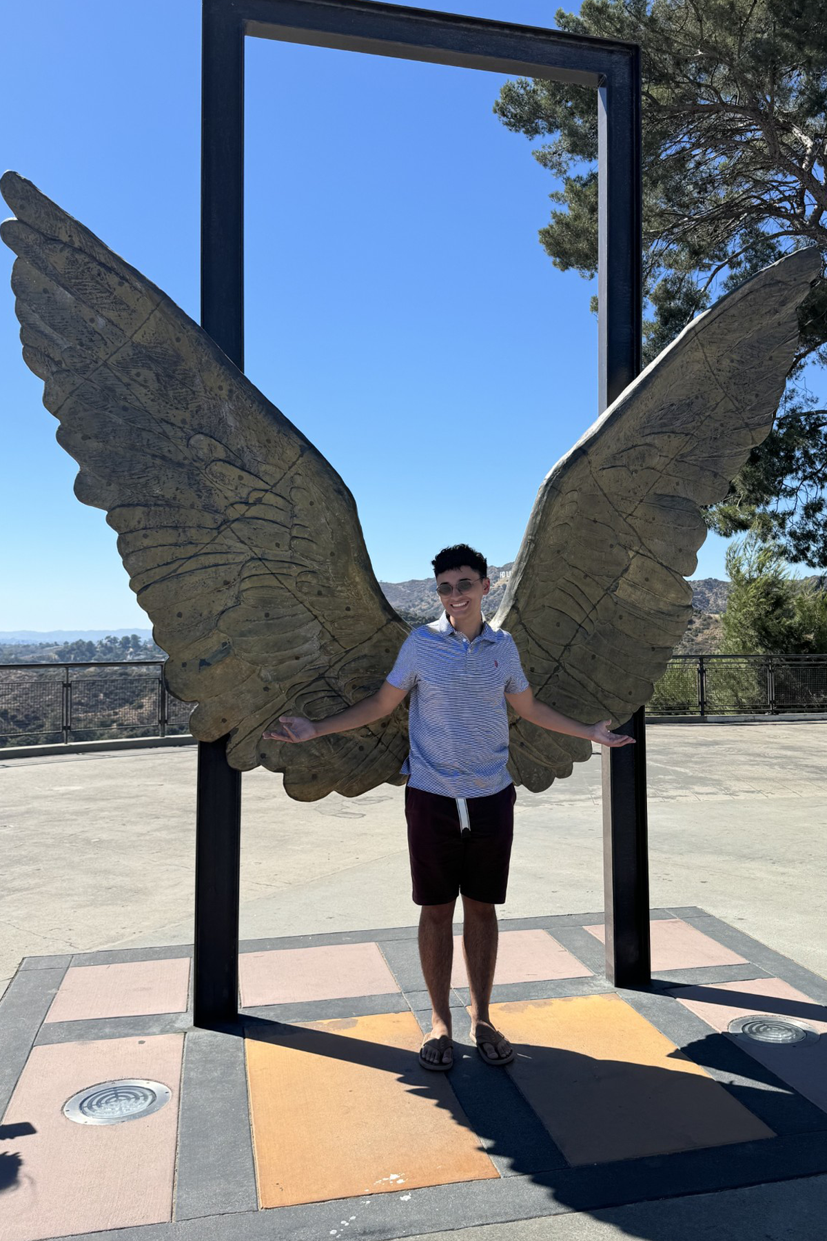 Yuliano Camarena standing with wings sculpture in background