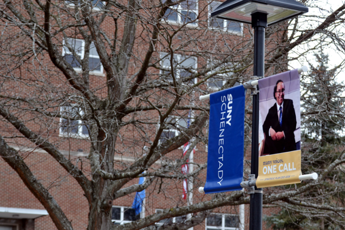 Trees on campus with College banner on flagpole.