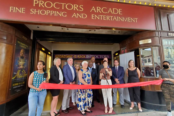 Officials cutting ribbon in front of Proctors