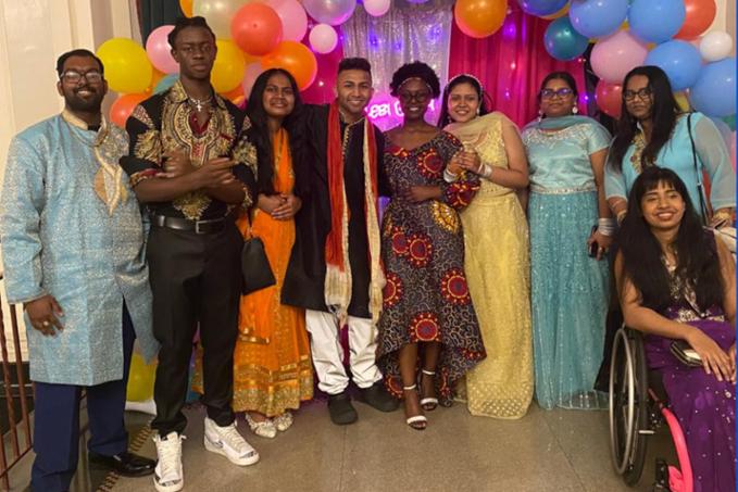 Guests in beautiful cultural attire pose for a photo with colorful backdrop