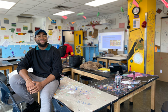 Tai Lopez sitting in art classroom, smiling at student