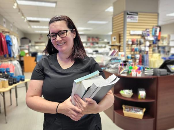 Jaime Noble standing, carrying books in front of College Store