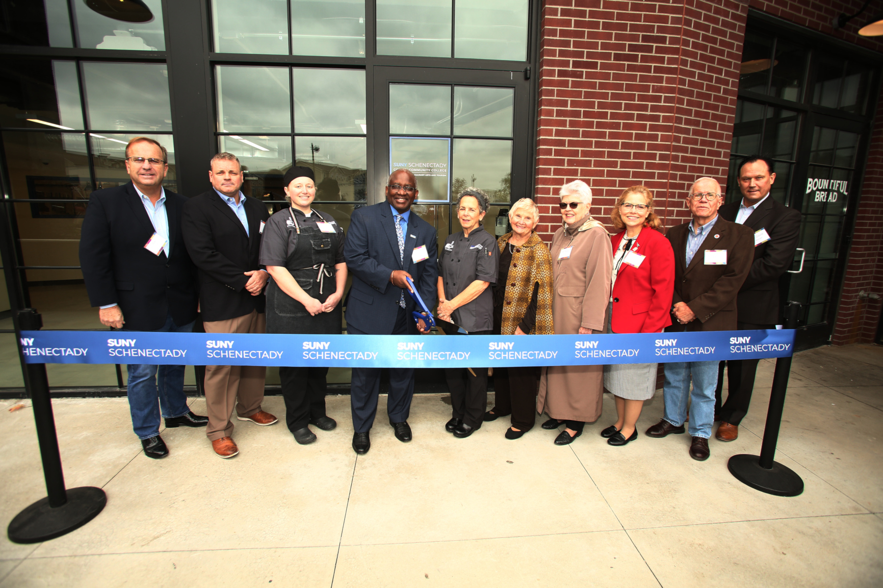 College officials cutting ribbon outside in front of new Confections Lab