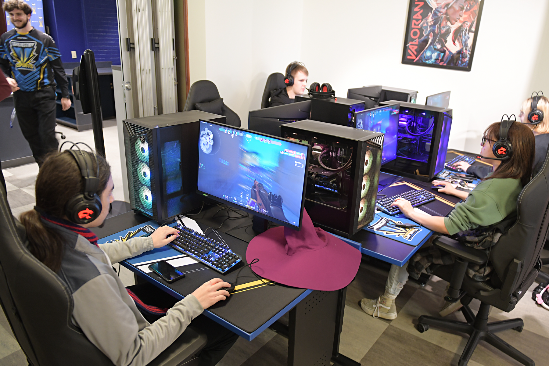 Five students seated, playing games on the gaming stations in the eSports arena.