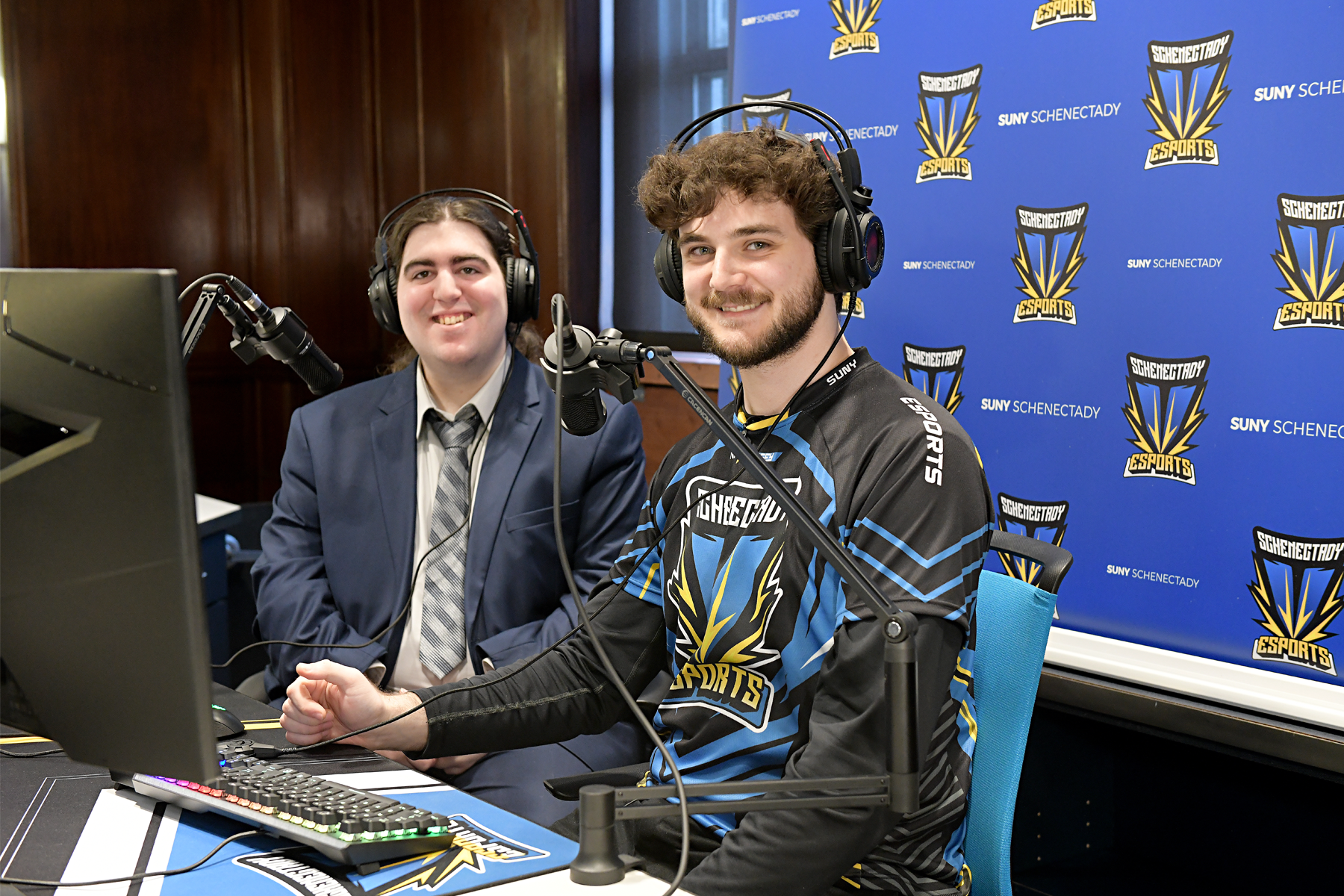 Student Daniel Van Buren and Cooper Hewison, eSports Specialst, seated in broadcasting booth. 