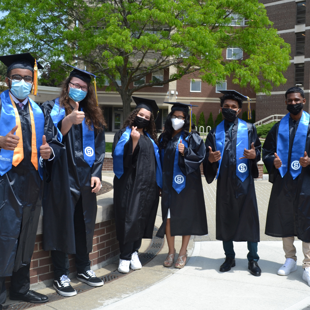 Smart Transfer graduates in cap and gown outside Elston Hall